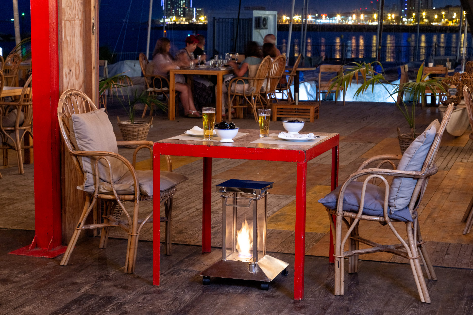 Estufa de bioetanol Calidor encendida junto a una mesa en la terraza frente al mar